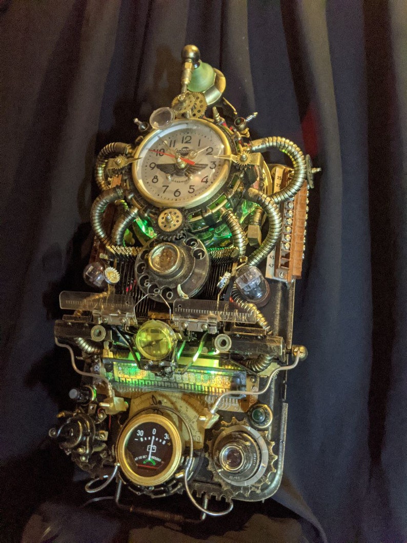 Puede incluir: Reloj de pared de estilo steampunk con acabado en lat&oacute;n y cobre. El reloj presenta una esfera redonda con n&uacute;meros romanos, engranajes, tubos y medidores. Luces verdes iluminan el interior, creando una est&eacute;tica industrial &uacute;nica.