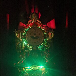 Puede incluir: Reloj de estilo steampunk con esfera redonda y detalles intrincados en lat&oacute;n y cobre. El reloj est&aacute; iluminado con luces LED verdes y rojas, creando un efecto dram&aacute;tico. El dise&ntilde;o incorpora engranajes, tubos y otros elementos mec&aacute;nicos.