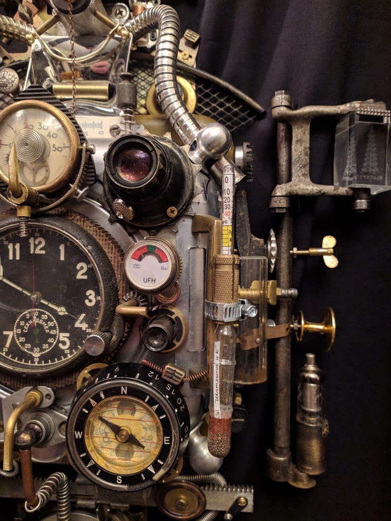 May include: A steampunk-style clock with a compass, thermometer, and other gauges. The clock face has Roman numerals and a second hand. The thermometer is labeled "Bar" and has a red needle pointing to 30. The compass is labeled "N" for north and has a needle pointing to the north.