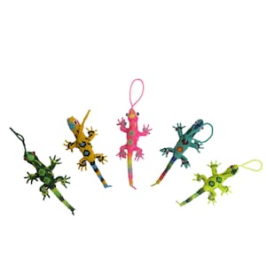 May include: Five lizard-shaped ornaments crafted from small colorful beads. The lizards are green, yellow, pink, blue, and lime green, each featuring a small loop at the top for hanging. The beadwork creates intricate patterns on each lizard figure.
