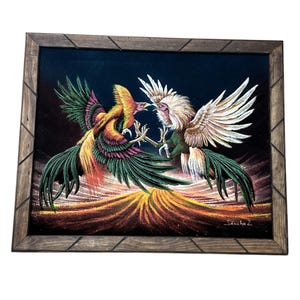 May include: A framed velvet painting depicting two roosters in a dynamic confrontation. The left rooster features vibrant green, yellow, and red plumage, while the right rooster has white and grey feathers. The artist signature Sancho Z is visible.