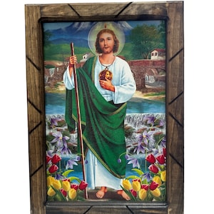 May include: A framed religious image of a man with a halo, wearing a green robe and holding a staff. The image is set against a backdrop of a mountain, a river, and a waterfall. The frame is made of wood and has a dark brown finish.