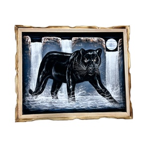 May include: A framed black velvet painting of a black panther walking through a waterfall with a full moon in the background.