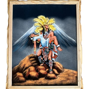 Puede incluir: Una pintura de terciopelo enmarcada que representa a un hombre con vestimenta tradicional azteca llevando a una mujer con un vestido blanco. El hombre lleva un tocado de plumas y la mujer est&aacute; inconsciente. La pintura est&aacute; sobre un fondo azul oscuro con una monta&ntilde;a en la distancia.