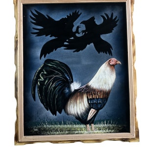 May include: A framed velvet painting of a rooster with a black, white, and brown plumage. The rooster is standing on a green field with a dark blue background. Two black silhouettes of birds are flying above the rooster.