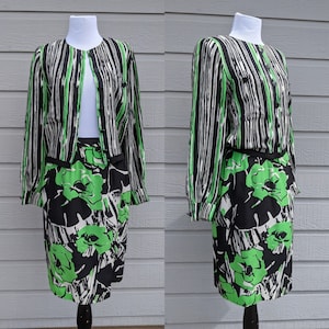 Könnte beinhalten: Ein schwarzes und grünes zweiteiliges Outfit mit einem gestreiften Oberteil und einem Blumenrock. Das Oberteil hat einen Knopfleisten vorne und lange Ärmel. Der Rock hat eine hohe Taille und eine figurbetonte Silhouette.
