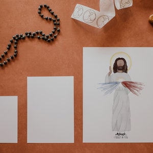 May include: A white card with a watercolor illustration of Jesus Christ with a red and blue heart on his chest. The text "Jesus, I trust in you" is written below the image.