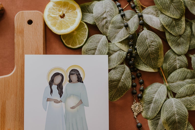 May include: A white card with a watercolour illustration of two women standing side-by-side. The woman on the right is pregnant and holding her belly. Both women have halos around their heads.