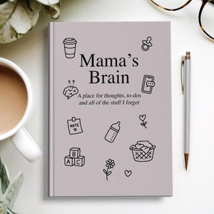Może przedstawiać: Jasnofioletowy notatnik z napisem "Mama's Brain" i tekstem "A place for thoughts, to-dos and all of the stuff I forget." Notatnik posiada czarne rysunki linii filiżanki kawy, mózgu, notatki, butelki dla dziecka i innych ikon.