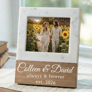 May include: A photo frame with a marble and wood design, displaying a picture of a couple in a sunflower field. The frame is inscribed with the names "Colleen & David", the words "always & forever", and the year "est. 2026".