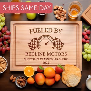 May include: Wooden serving tray with the text "Fueled By Redline Motors Suncoast Classic Car Show 2025" and a speedometer graphic. The tray is surrounded by grapes, nuts, fruit, and crackers.
