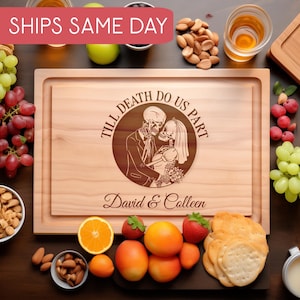 May include: A wooden cutting board with a decorative engraved design featuring a skeleton couple and the text "Till Death Do Us Part" and the names "David & Colleen". The board is surrounded by snacks and drinks.