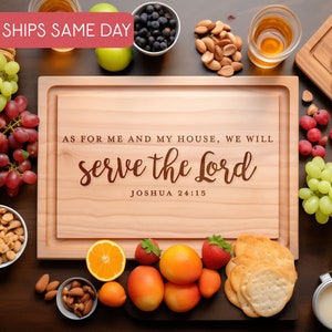 May include: A wooden chopping board with the text "AS FOR ME AND MY HOUSE, WE WILL serve the Lord JOSHUA 24:15" engraved on it. The board is surrounded by various fruits, nuts, and snacks.