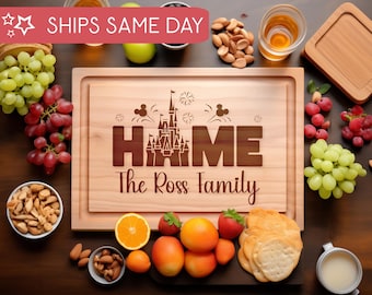 May include: A wooden cutting board with a laser engraved design of Cinderella's castle and the words "Home The Ross Family". The board is surrounded by various snacks and drinks, including grapes, nuts, crackers, and a glass of whiskey.