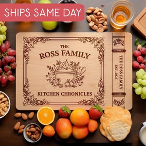 May include: A wooden cutting board with the text "THE ROSS FAMILY KITCHEN CHRONICLES" and a decorative illustration of a pot and vegetables. The board is surrounded by grapes, nuts, fruit, and crackers.