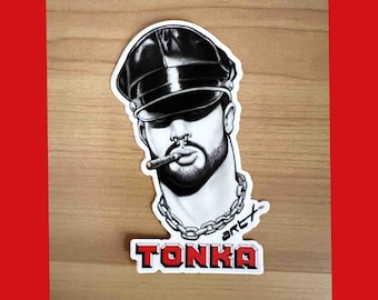 May include: Black and white illustration of a man with a leather cap, a chain necklace, and a cigarette in his mouth. The text "TONKA" is printed below the image.