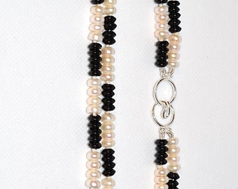 Puede incluir: Un collar de doble cadena hecho de cuentas blancas y negras con un cierre de plata.