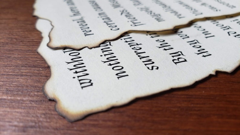 May include: A close-up of two pieces of paper with text written in a black font. The paper is torn and burnt around the edges, giving it an aged and distressed look. The text reads "withho", "surrepti", "certain ca", "nothing", "reveal here", "they we myself, Ra", "Ince realizun", "Bu the ti", "friends. Mis".
