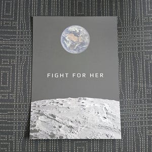 May include: A dark gray print featuring an image of Earth and the lunar surface. The text "FIGHT FOR HER" is centered on the print. The Earth is depicted in shades of blue, brown, and white, while the moon is in shades of gray.