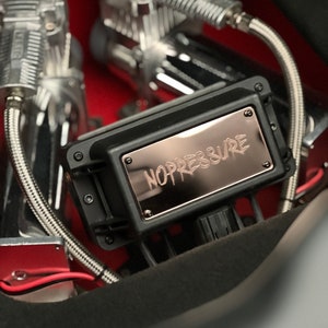 May include: A black metal box with a rose gold plate that says "NOPRESSURE" in a stylized font. The box is attached to two silver air compressor pumps.
