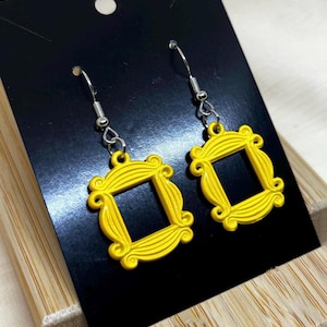 May include: A pair of yellow dangle earrings shaped like the iconic frame from the TV show "Friends".