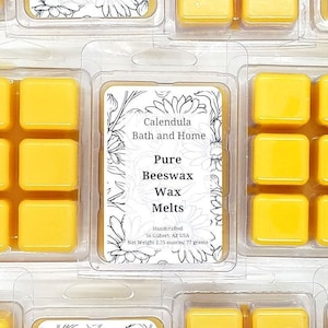 Puede incluir: Seis cubos de cera amarilla en un recipiente de plástico transparente. La etiqueta dice "Calendula Bath and Home Pure Beeswax Wax Melts Handcrafted in Gilbert, AZ USA Net Weight 2.75 ounces/77 grams".