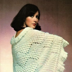 May include: A white crocheted shawl with a lacy border. The shawl is draped over a person's shoulders and is made with a delicate stitch pattern.