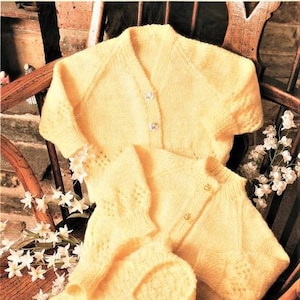 以下が含まれることがあります： 黄色のニットのベビーカーディガンとパンツのセット。カーディガンはボタン留め、パンツはシンプルなデザインです。