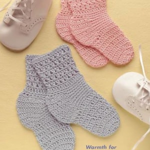 May include: Two pairs of crocheted socks, one pair is pink and the other is gray. The socks are laid out on a light yellow surface. The text "Warmth for your favorite pair of feet." is printed below the socks.