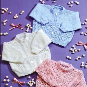 Puede incluir: Tres cárdigans de punto para bebé en diferentes colores: azul claro, blanco y rosa. Cada cárdigan tiene un cierre de botones en la parte delantera y un delicado patrón de encaje.