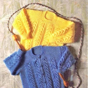 May include: Two knitted cardigans, one yellow and one blue, with a rope-like texture and a chevron pattern. The cardigans are laid out on a textured surface.