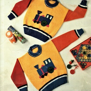 May include: Two yellow knit sweaters with red and blue trim. Each sweater features a blue train with black wheels and a white smoke plume.