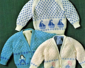 May include: Three knitted baby sweaters in different colors and patterns. One sweater is white with blue polka dots and a sailboat design. Another sweater is blue with white polka dots and a girl design. The third sweater is white with pink flowers and blue polka dots.