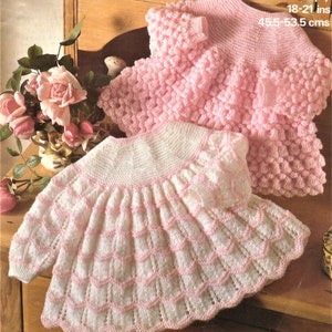 May include: Two knitted baby dresses, one white with pink trim and a scalloped hem, and one pink with a textured stitch. The dresses are made with 4 ply yarn and are 18-21 inches long.