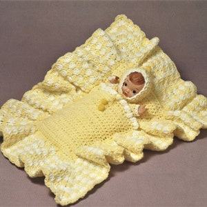 May include: A crocheted baby blanket in yellow and white with a doll inside. The blanket has a ruffled edge and a crocheted hood.