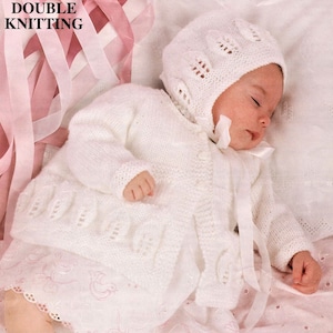 May include: A white knitted baby cardigan and matching bonnet with a delicate lace pattern. The set is made with a soft yarn and features a button closure on the cardigan.