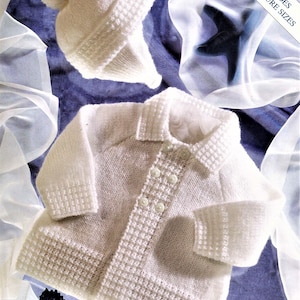 May include: White knitted baby cardigan with a button fastening and matching hat. The set includes premature sizes.