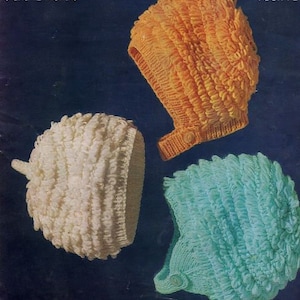 May include: Three knitted baby hats in different colors: white, orange, and blue. The hats are made with a textured stitch and have a button on the side.
