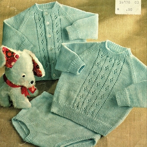 Può includere: Un set di maglieria per neonato di colore azzurro chiaro composto da un maglione e pantaloni abbinati con un delicato motivo a pizzo. Il set è disposto su uno sfondo di juta marrone.