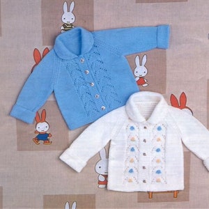 May include: Two knitted baby cardigans, one blue with a lacy pattern and one white with a floral design. Both cardigans have button fastenings and a collar.