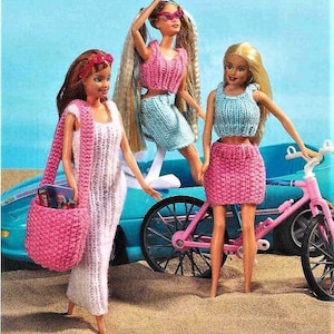 May include: Three dolls wearing knitted outfits. The doll on the left is wearing a white dress with a pink bag. The doll in the middle is wearing a blue and pink knitted top and skirt. The doll on the right is wearing a blue knitted top and a pink skirt. The dolls are standing in front of a blue car and a pink bicycle.
