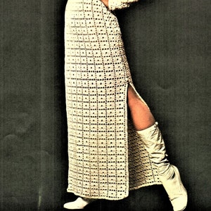 May include: A long, white crochet dress with a side slit and a geometric pattern. The dress is worn with white boots.