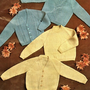 May include: Four knitted sweaters in blue and yellow. Two of the sweaters are cardigans with buttons and two are pullovers. The sweaters are laid out on a brown surface.