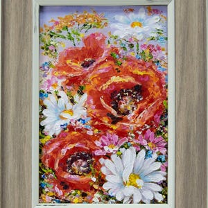 Puede incluir: Pintura floral enmarcada con amapolas naranjas vibrantes, margaritas blancas y otras flores coloridas. La obra de arte está sobre un fondo morado claro y enmarcada en un marco de madera marrón claro.