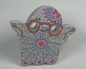 May include: A hand-painted gray ghost figurine with a pink, purple, and yellow mandala design. The ghost is wearing brown glasses and has a happy expression.