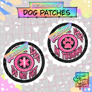 May include: Two circular patches with scalloped white edges. One patch features a pink medical symbol and the text 'SERVICE DOG DO NOT PET'. The other patch displays a pink paw print and the text 'SERVICE DOG IN TRAINING'. Both have black borders.