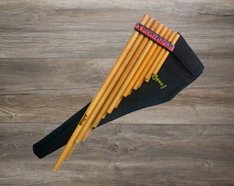 May include: A wooden panpipe with a black carrying case and a colourful strap. The panpipe is made of natural bamboo and has a green label that says "Sopeca".