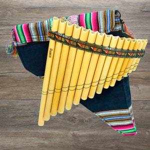May include: A wooden panpipe with a black and colourful fabric carrying case. The panpipe has a brown leather strap and the text "Ramos" is printed on the side.