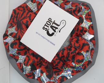 May include: A cat collar with a red and black pattern, accented with silver holographic foil. The collar has a gray border and a white tag that reads "STOP CAT" and "www.lifexcollars.co.uk".