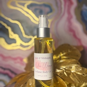 May include: A clear glass bottle of perfume body oil with a silver spray top. The label reads "Mist & Midnight" and "Milar Aromas". The bottle contains a yellow liquid and is set against a gold and pink background. The bottle contains 4 fl oz / 118 ml.